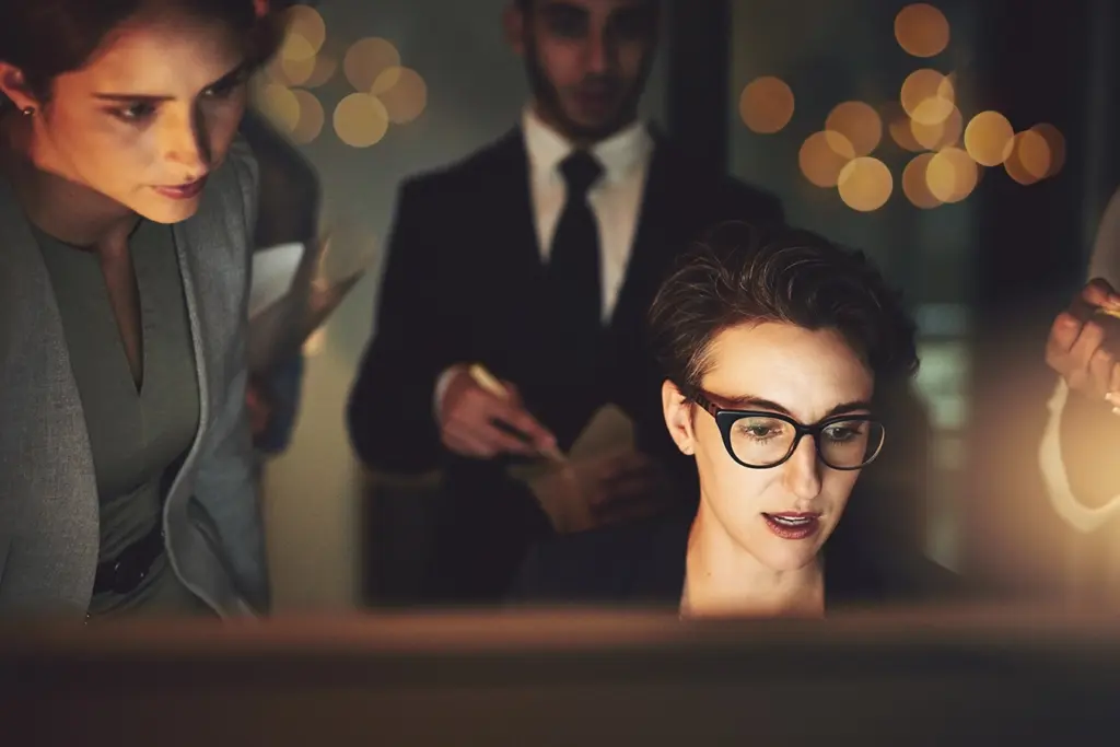 Personer som granskar information pa datorskarm i kontorsmiljo – illustration av oversikt, rapporter och kontroll over foretagets natverk.