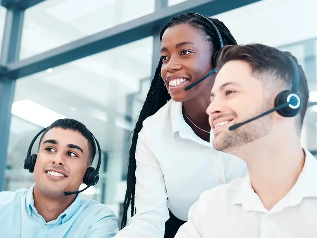 Tre personer med headset i kontorsmiljö som arbetar med IT‑support