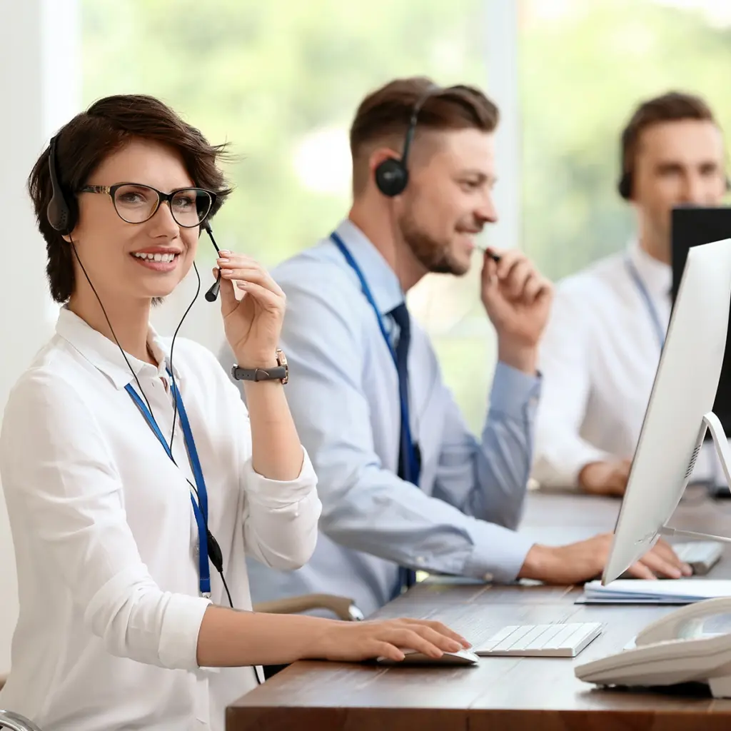 Personer i kontorsmiljo med headset som arbetar vid datorer – illustration av snabb lokal IT‑support, service desk och modern arbetsplatslosning for foretag i Stockholm.