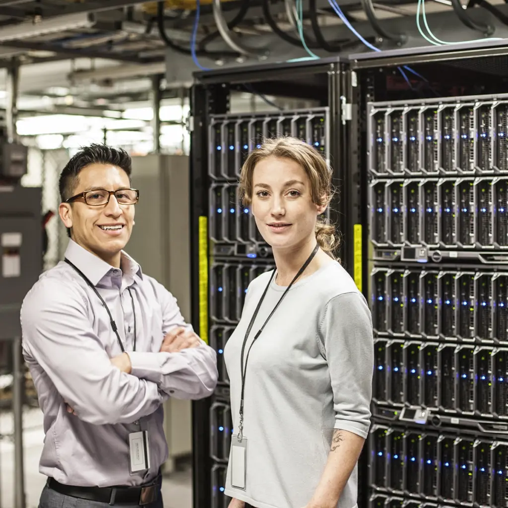 Två personer står framför serverrack i en serverhall.