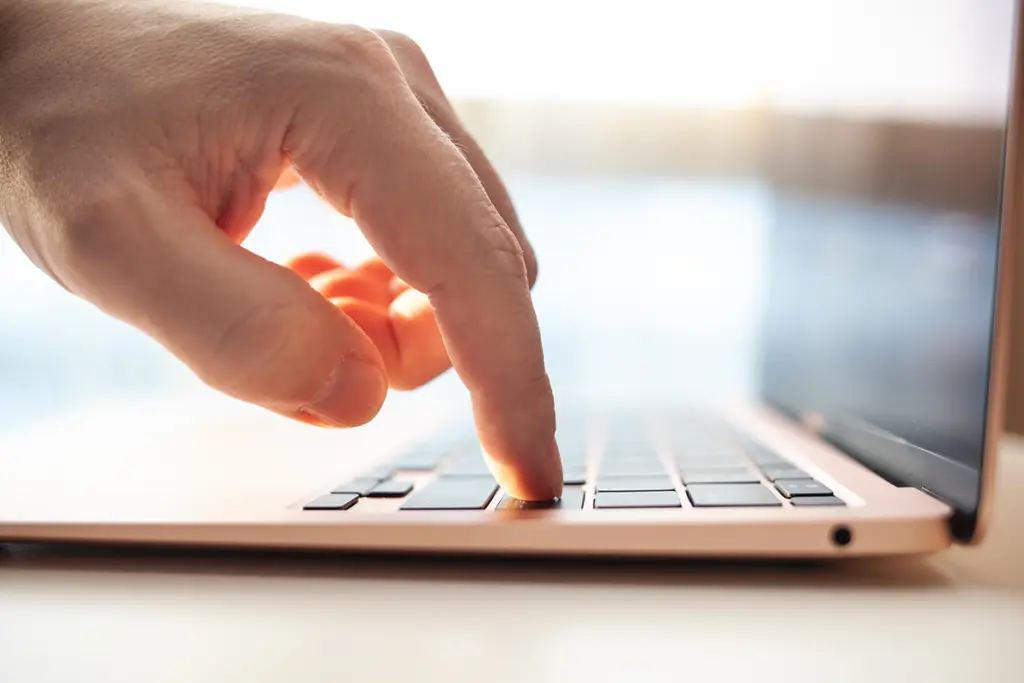 Närbild av en hand som trycker på tangentbordet på en bärbar dator.