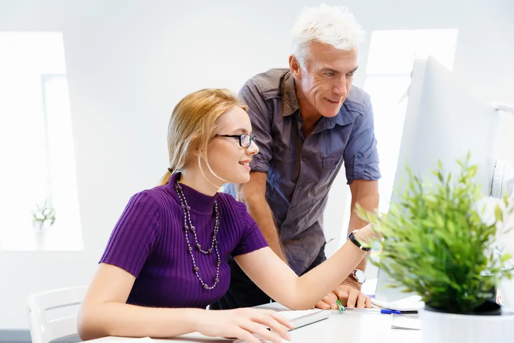 Två personer arbetar vid en stationär dator med texten ”Kom igång med ny dator”.