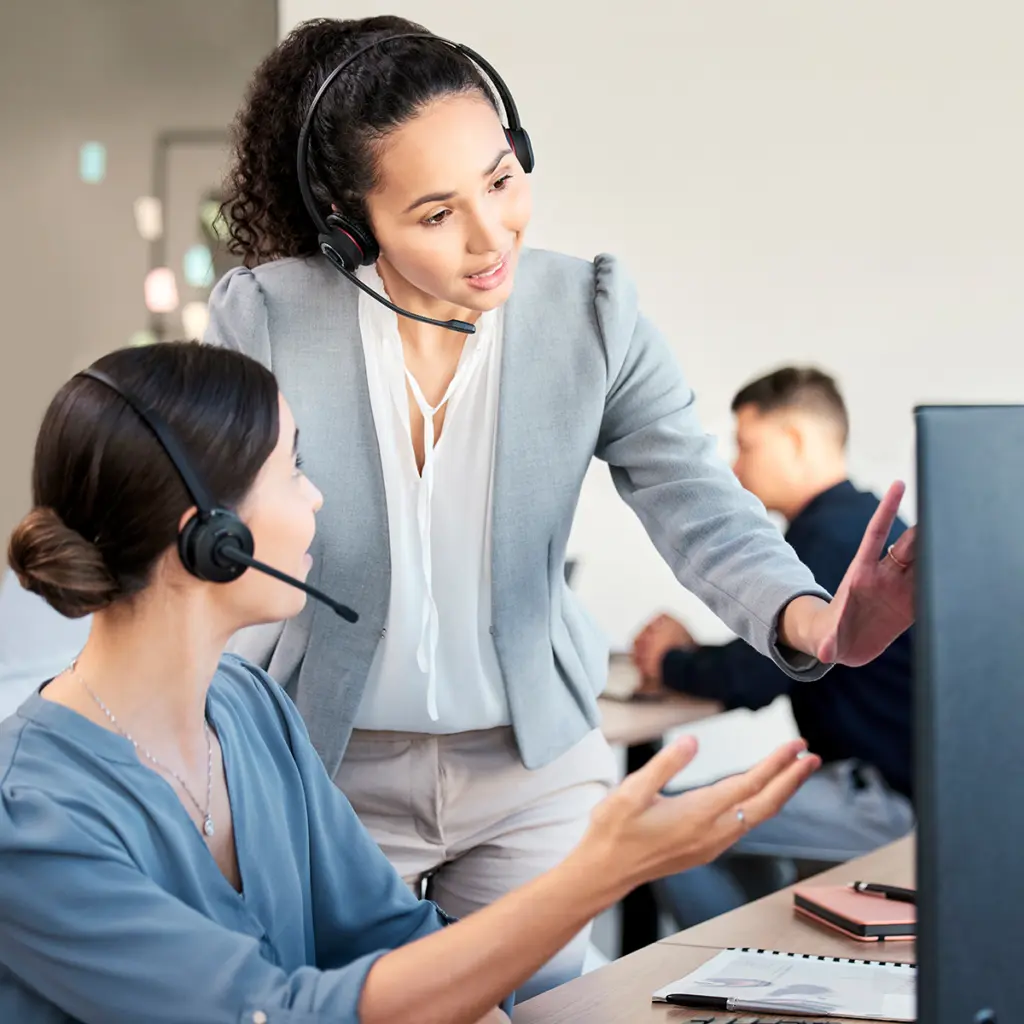 Supportmedarbetare med headset arbetar vid dator i kontorsmiljö